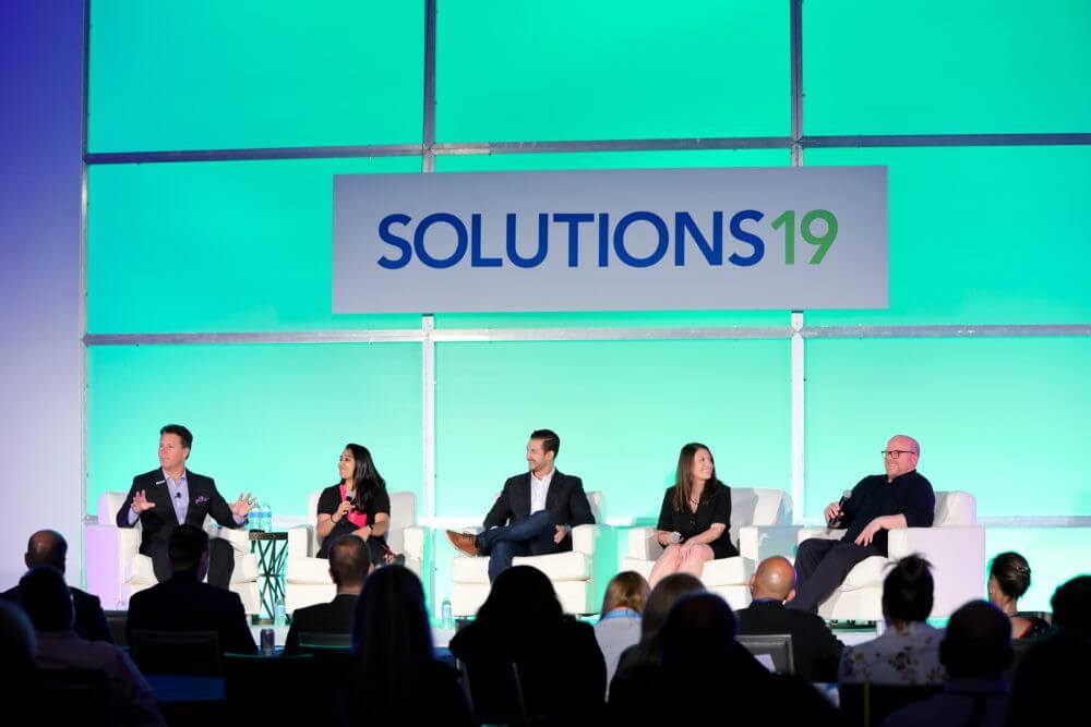 Solutions 19 photo of people on stage speaking to a crowd of business people